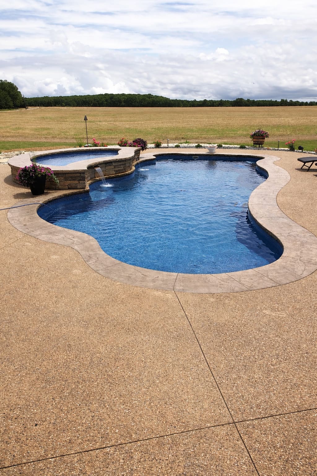 Freeform pool with spillover spa facing open grass field