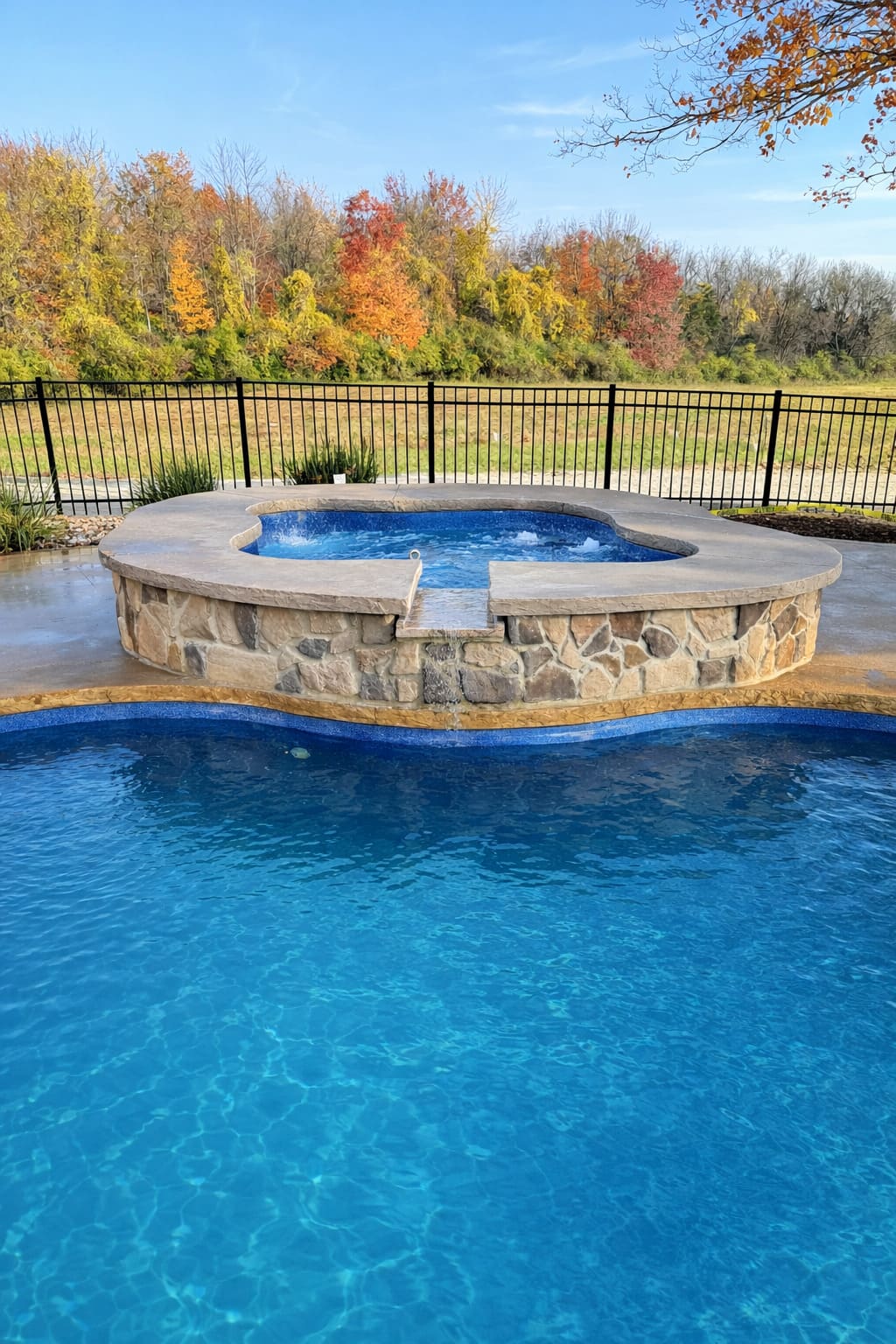 Raised spillover spa with autumn trees and lawn