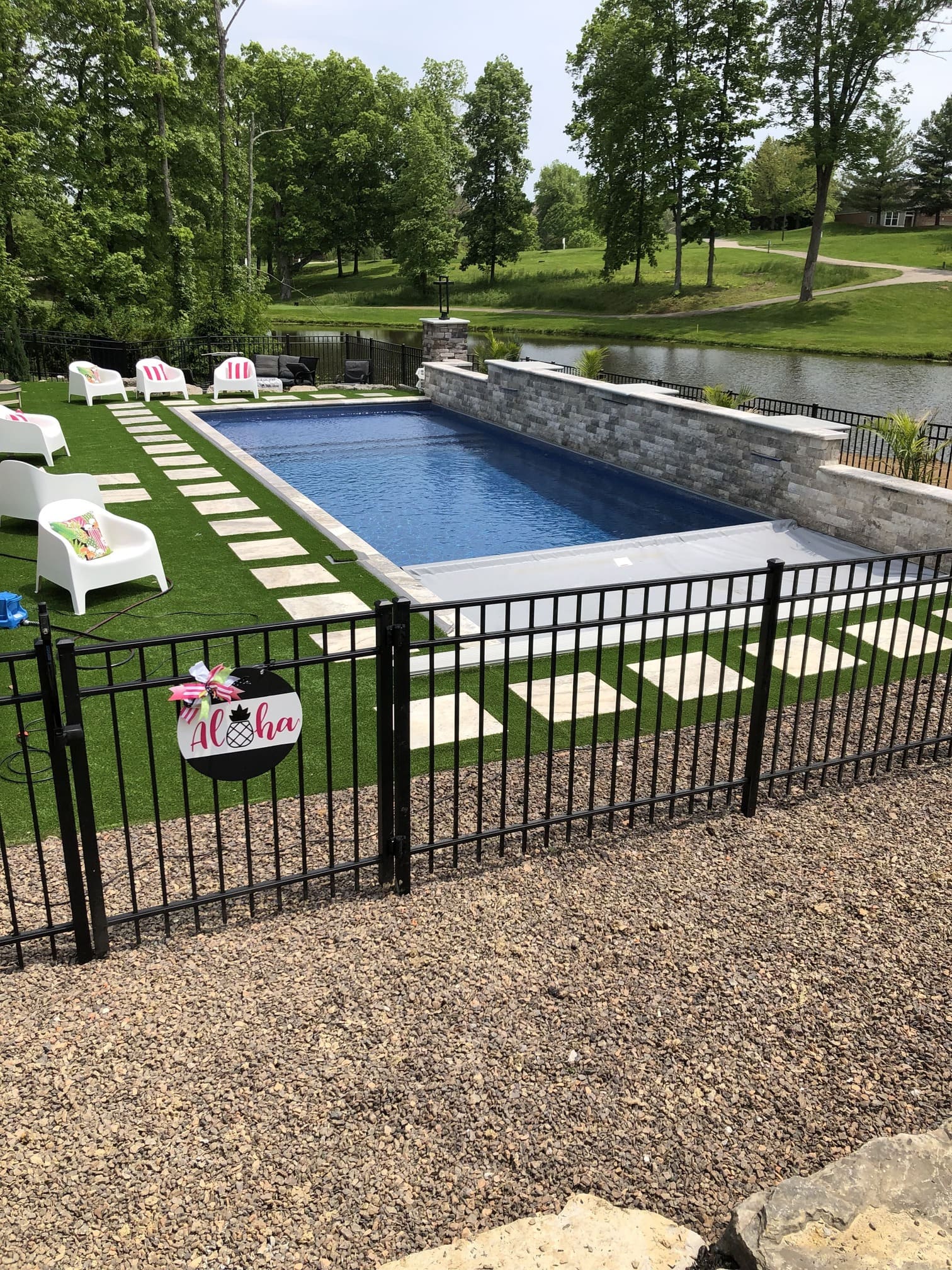Finished rectangular fiberglass pool with turf loungers overlooking a pond and wooded edge