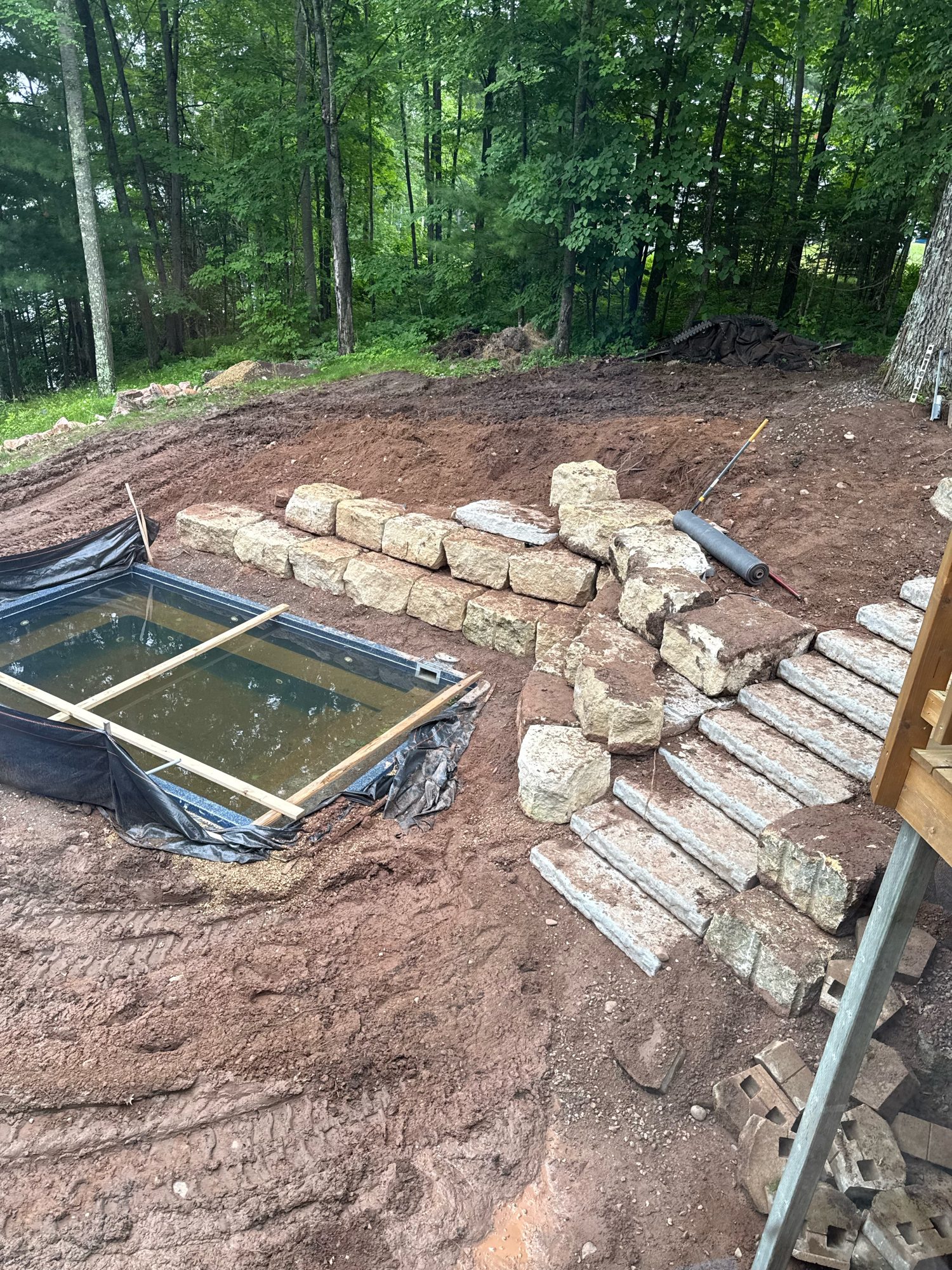 Latham Milan shell in excavation with limestone retaining wall and stone stairs, Long Lake WI install in progress