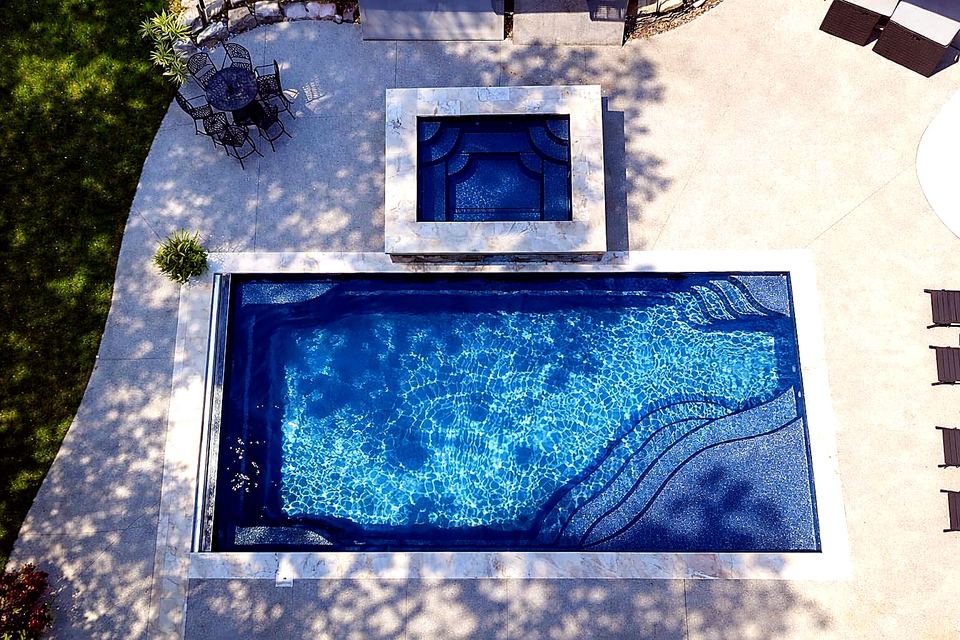 Rectangular fiberglass pool with an automatic cover on a concrete deck
