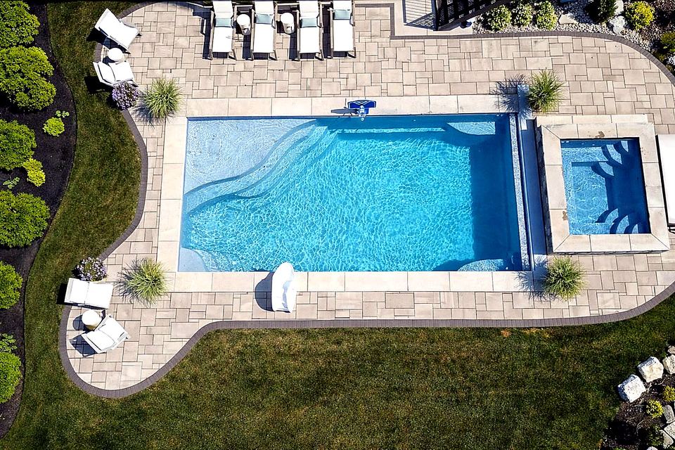 Medium rectangular fiberglass pool with spa and gray paver deck