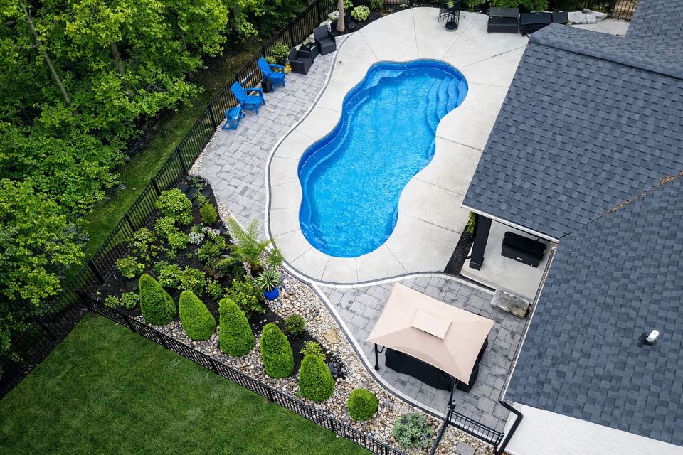 Aerial freeform pool with lush plantings and wooded lawn patio