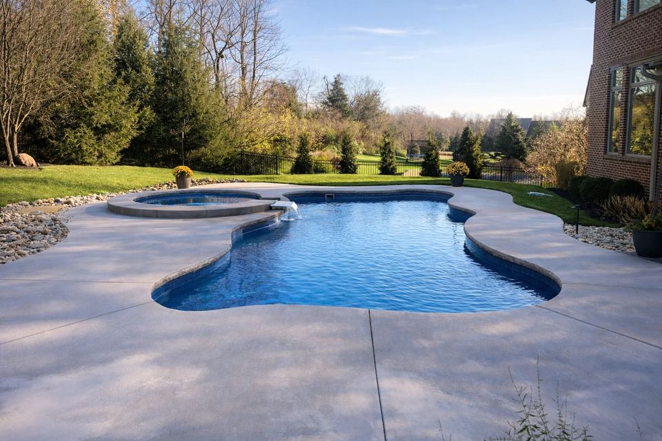 Freeform pool with circular spa waterfall and wooded lawn