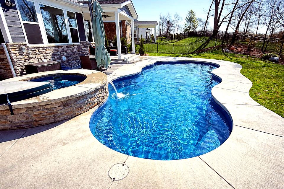 Freeform fiberglass pool with a circular spa and sheer waterfall