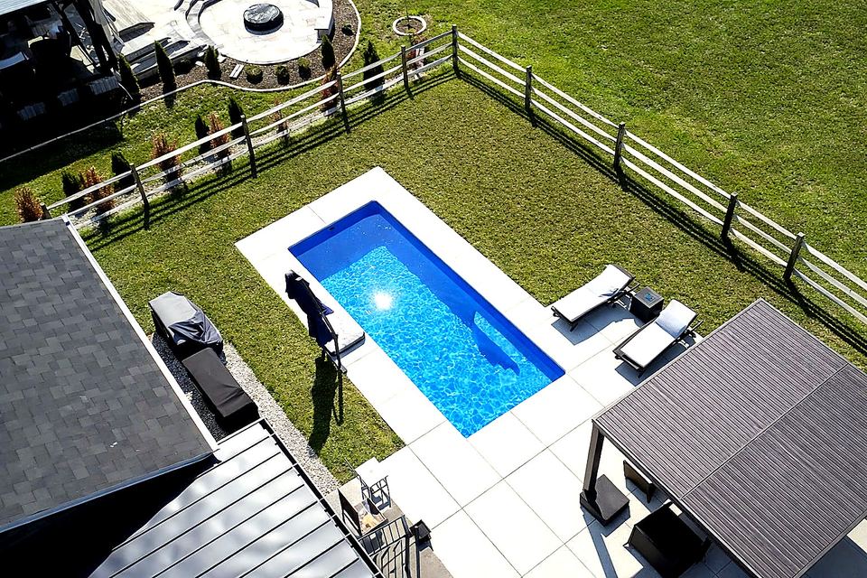 Aerial view of a small rectangular fiberglass pool with a concrete deck